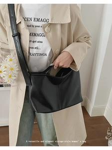 Chic black matte leather shoulder bag worn by model over a beige trench coat for commute