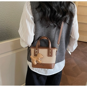Détail d'un sac seau bicolore avec bijou de sac chiot porté par un mannequin de dos