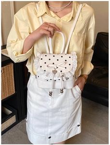 Détail d'un sac à dos blanc à pois avec dentelle, nœud élégant et pendentif en forme de cœur