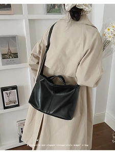 Detailed view of black leather tote bag with matte texture and minimalist trapezoidal shape