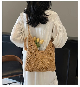 Detail of woven straw tote bag with elegant tassel charm and hollow-out knitting pattern