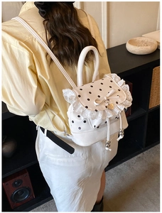 Détail du sac à dos à pois blancs avec bordure en dentelle et pendentif coeur doré