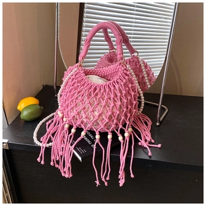 Dettaglio borsa intrecciata rosa con nappe lunghe, perline di legno e catena di perle