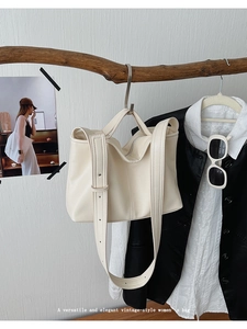 Detail view of cream vintage tote bag with wide strap hanging on wooden branch decoration