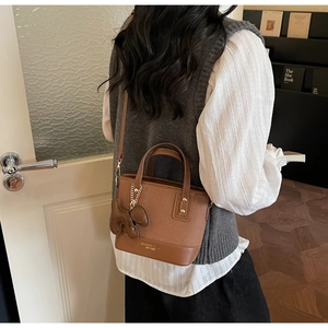 Sac seau marron avec pendentif ours et détails de rivets dorés sur cuir texturé