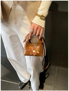 Détail d'un mini sac bandoulière marron matelassé avec broderie poney et poignée