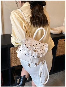 Détail du mini sac à dos blanc à pois avec bordure en dentelle et pendentif cœur