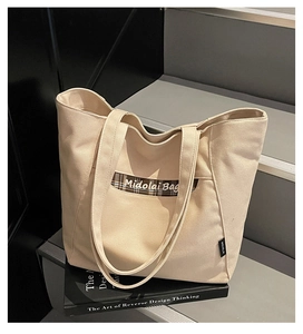 Dettaglio della borsa tote in tela con bordo scozzese e logo Midolai Bag sulla tasca
