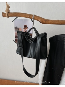 Close-up of black vintage tote bag with fine leather texture hanging on a branch