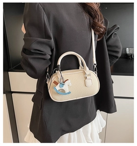 Dettaglio della borsa beige crema in pelle martellata con ciondolo a forma di cavallo