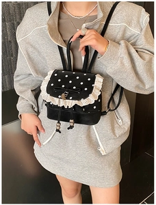 Détail du mini sac à dos à pois avec bords en dentelle blanche et un nœud noir élégant