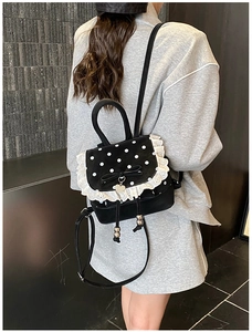 Vue détaillée d'un mini sac à dos noir à pois blancs avec bordure en dentelle