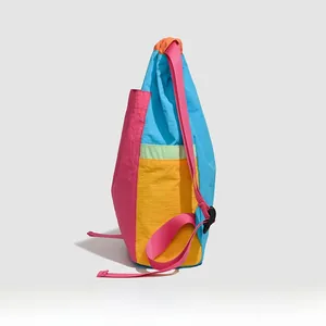 Side view of multi-color drawstring backpack in pink, blue and yellow waterproof nylon