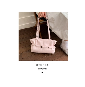 Dettaglio della borsa tote rosa con fibbie regolabili su pavimento in legno