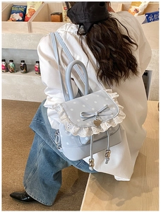 Sac à dos bleu clair à pois avec dentelle et nœud porté dans un café moderne