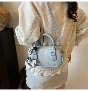 Dettaglio della borsa bowling azzurra in pelle con texture litchi e un ciondolo a cavallo