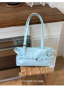 Dettaglio borsa tote in pelle PU azzurra con trama stropicciata e fibbia decorativa