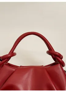 Dettaglio della borsa rossa che mostra l'unico manico annodato e arrotondato