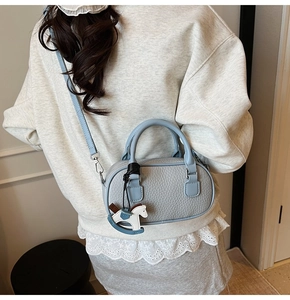 Detail of light blue pebble leather bowling bag with horse charm and shoulder strap