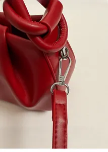 Dettaglio della borsa in pelle PU rossa con texture arricciata e fibbia argentata