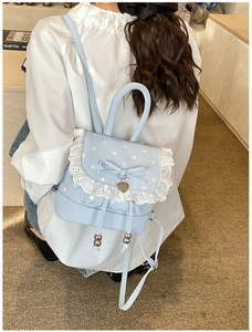 Détail du sac à dos bleu clair à pois avec bordure en dentelle blanche et nœud