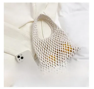 Detail of white handmade woven cotton net bag with smartphone for size comparison