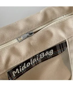 Dettaglio della borsa in tela con cerniera in metallo liscia e logo ricamato