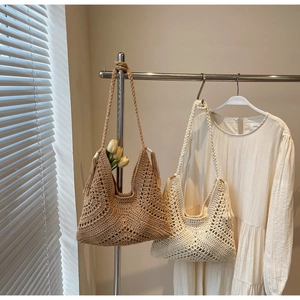 Detail of hand-woven hollow knit tote bag with tassel charms and braided strap