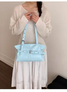 Dettaglio della borsa tote azzurra stropicciata con fibbia decorativa su outfit crema