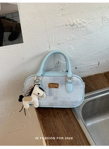 Detail of light blue leather handbag with zebra pattern horse charm and gold plaque