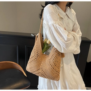 Detail of woven straw tote bag featuring intricate openwork patterns and fringe tassels