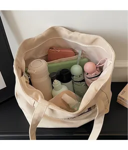 Dettaglio dell'interno spazioso della borsa tote in tela crema con tasche e vari oggetti