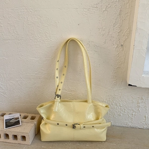 Dettaglio della borsa tote giallo chiaro con texture lucida stropicciata e fibbie metalliche