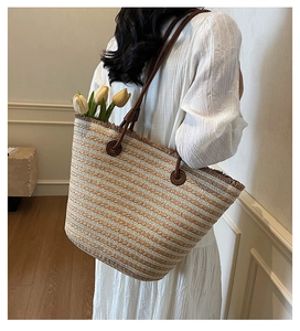 Detail of woven straw tote bag with brown stripes and leather straps for beach vacation