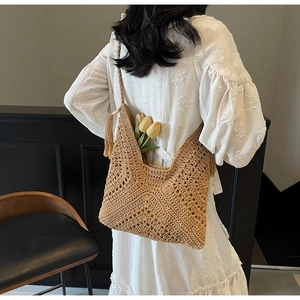 Detail of a brown crochet tote bag with rhombus cutouts and stylish fringe tassels