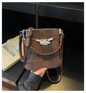 Detail of dark brown checked bucket bag with silver geometric buckle and woven handle
