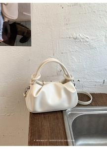 Dettaglio borsa a mano pieghettata bianco crema con manico annodato e finiture argentate