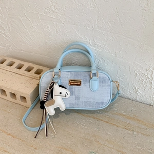 Close-up of light blue Boston bag with plaid patterns and a horse-shaped leather charm