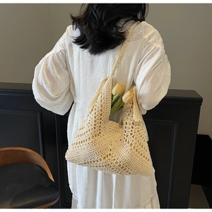 Detail of cream woven shoulder bag featuring geometric crochet patterns and fringe charms
