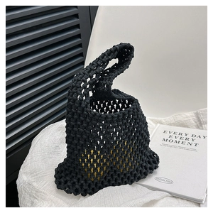 Detail of black hand-woven mesh handbag showing the vibrant yellow inner lining contrast