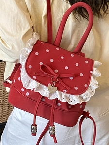 Sac à dos mignon rouge à pois avec dentelle blanche et pendentif nœud sur un modèle