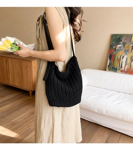 Detail of black woven knit tote bag with premium leather shoulder strap in cozy indoor setting