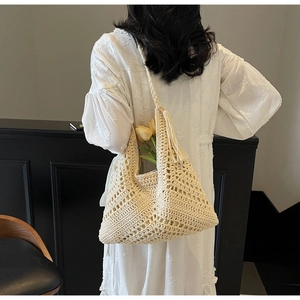 Detailed view of cream crochet tote bag with fringe tassels and woven shoulder strap