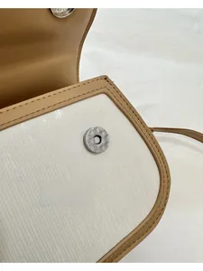 Gros plan sur la boucle métallique et la texture du tissu d'un petit sac beige