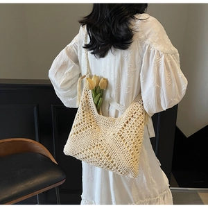 Detail shot of the cream crochet hollow diamond knit pattern and bohemian tassels on the bag
