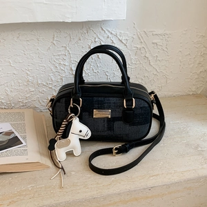 Close-up of a dark grey Boston bag featuring a gold fashion plaque and white pony charm