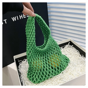 Detail view of a green hand-woven mesh tote bag with citrus fruits in a white gift box