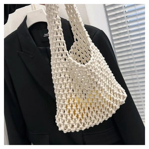 Detail shot of the white woven handbag with intricate hollow mesh texture and sturdy cotton ropes
