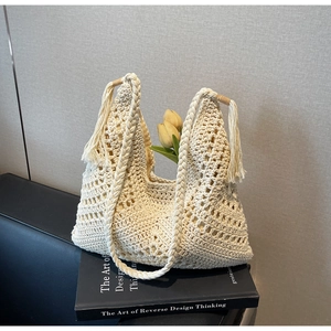 Close-up of beige crochet hobo bag with tassel details and hollow woven texture