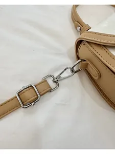Détail du fermoir mousqueton argenté et de la boucle réglable sur le sac beige